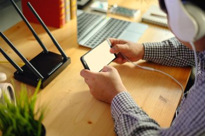 Środkowa sekcja mężczyzny używającego smartfonu siedząc przy biurku w biurze
