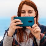 Turysta kaukaski kobieta robi zdjęcia na telefon w pobliżu oceanu