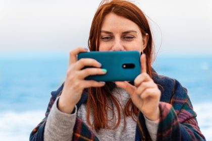 Turysta kaukaski kobieta robi zdjęcia na telefon w pobliżu oceanu