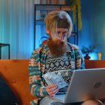 Kobieta używająca laptopa siedząc w domu na kanapie