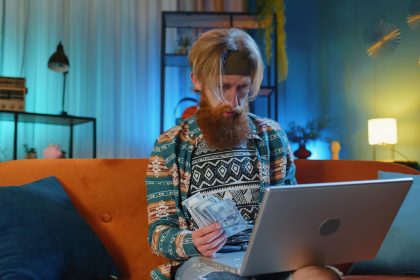 Kobieta używająca laptopa siedząc w domu na kanapie
