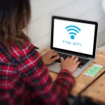 Z tyłu widok kobiety używającej laptopa na stole