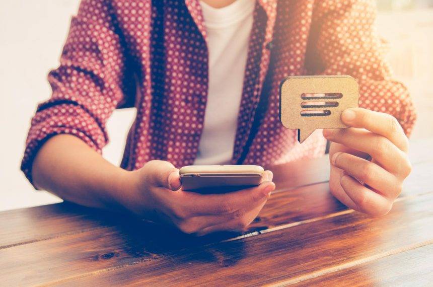 Środkowa sekcja mężczyzny trzymającego smartfon i znak na stole