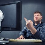 Mężczyzna siedzący przy biurku, patrząc na ekran komputera