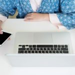 Środkowa sekcja kobiety biznesmenki używającej telefonu komórkowego przy biurku w biurze