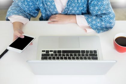 Środkowa sekcja kobiety biznesmenki używającej telefonu komórkowego przy biurku w biurze