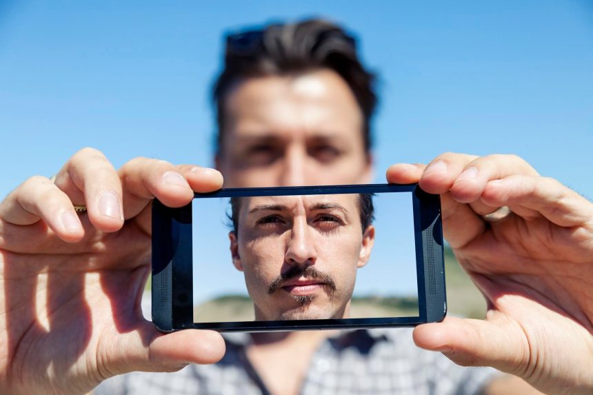 Młody, uroczy dorosły robi selfie ze smartfonem.