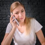 Portret pięknej młodej kobiety używającej telefonu komórkowego na ścianie