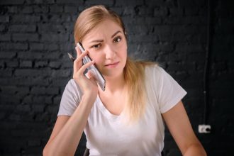 Portret pięknej młodej kobiety używającej telefonu komórkowego na ścianie