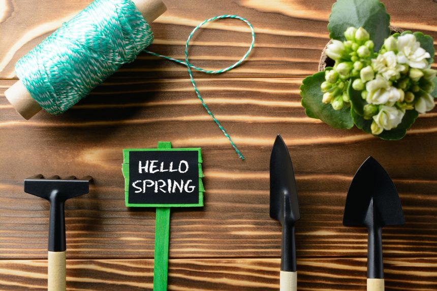 Z góry napis Hello Spring i narzędzia ogrodnicze na drewnianym stole