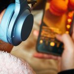 Widok z tyłu nastolatki używającej telefonu komórkowego z słuchawkami