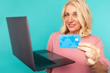 Zakupy na komputerze. Uśmiechnięta kobieta z laptopem i kartą kredytową robi zakupy online.