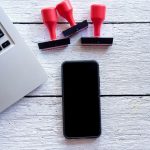Bezpośrednio powyżej zdjęcia smartfona i laptopa z znaczkami na stole