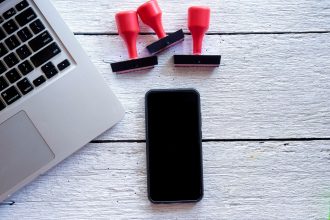 Bezpośrednio powyżej zdjęcia smartfona i laptopa z znaczkami na stole