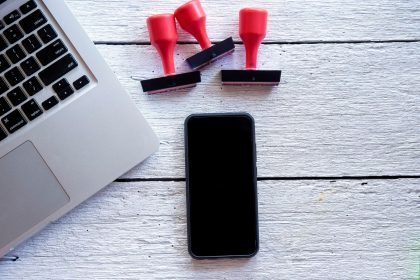 Bezpośrednio powyżej zdjęcia smartfona i laptopa z znaczkami na stole