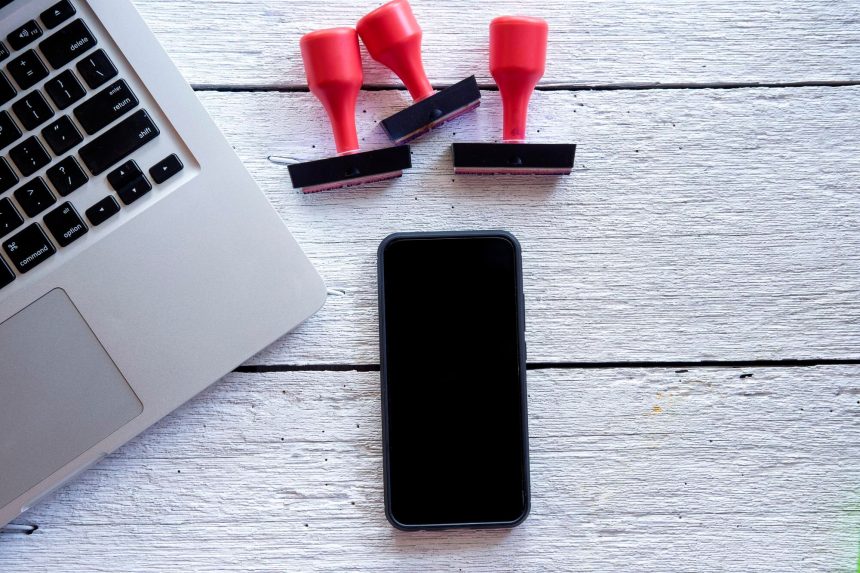 Bezpośrednio powyżej zdjęcia smartfona i laptopa z znaczkami na stole