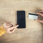 Kobieta wręcza telefon i kartę kredytową na stole