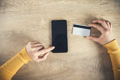 Kobieta wręcza telefon i kartę kredytową na stole