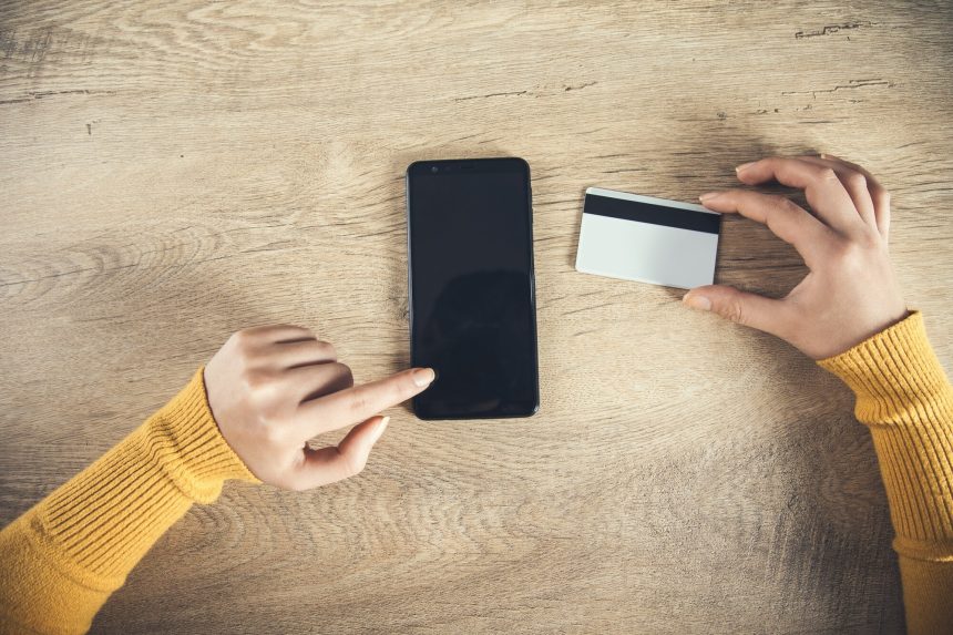 Kobieta wręcza telefon i kartę kredytową na stole