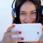 Letni portret pięknej kobiety z długimi ciemnymi włosami słuchającej muzyki na słuchawkach