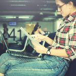 Kobieta wykonująca papierkową robotę przy użyciu laptopa na lotnisku