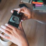 Środkowa część kobiety fotografującej ze smartfonem na stole