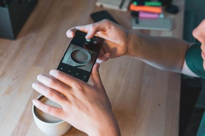 Środkowa część kobiety fotografującej ze smartfonem na stole