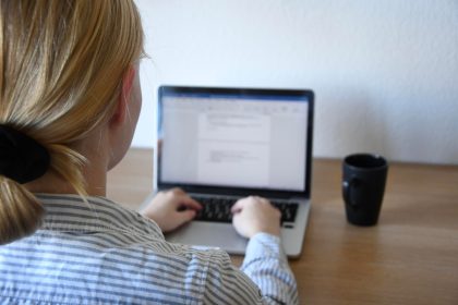 Z tyłu widok kobiety używającej laptopa w domu