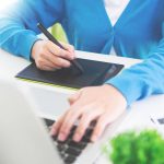 Środkowa sekcja bizneswoman używająca tabletu graficznego i laptopa przy biurku