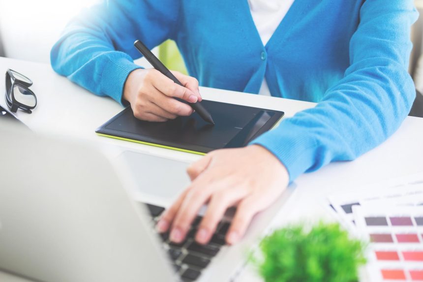 Środkowa sekcja bizneswoman używająca tabletu graficznego i laptopa przy biurku