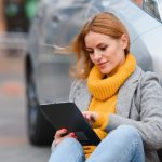 Kobieta w pobliżu wypożyczonego samochodu elektrycznego. Pojazd ładowany na stacji ładowania.