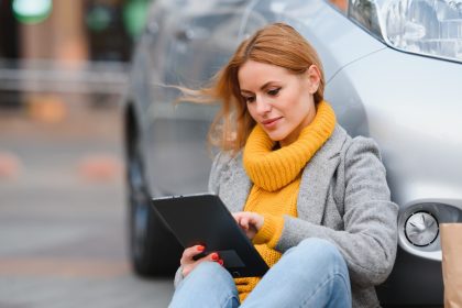 Kobieta w pobliżu wypożyczonego samochodu elektrycznego. Pojazd ładowany na stacji ładowania.