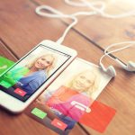 koncepcja technologii, komunikacji, gadżetu i obiektu - zbliżenie białego smartfona i słuchawek na drewnianej powierzchni z połączeniem przychodzącym na ekranie