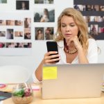 Kobieta grafik przy biurku przy użyciu telefonu komórkowego