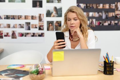 Kobieta grafik przy biurku przy użyciu telefonu komórkowego