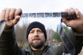 Mężczyzna z zainteresowaniem patrzy na starożytny film fotograficzny Koncepcja genealogii Pamięć o przodkach więzi rodzinne wspomnienia z dzieciństwa Historia i przeszłość Stare negatywy fotograficzne