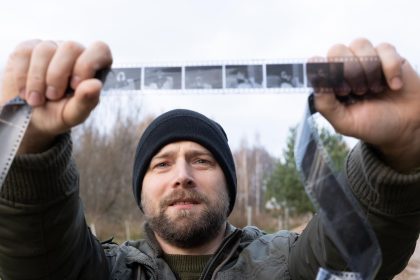 Mężczyzna z zainteresowaniem patrzy na starożytny film fotograficzny Koncepcja genealogii Pamięć o przodkach więzi rodzinne wspomnienia z dzieciństwa Historia i przeszłość Stare negatywy fotograficzne