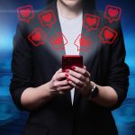 Zbliżenie rąk kobiety używającej smartfona z ikonami takimi jak serca
