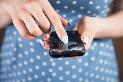 Młoda kobieta naciska na zepsuty ekran telefonu