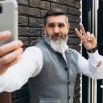 Siwowłosy brodaty starszy mężczyzna robi selfie