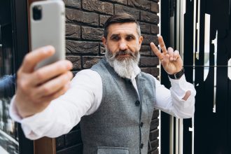 Siwowłosy brodaty starszy mężczyzna robi selfie