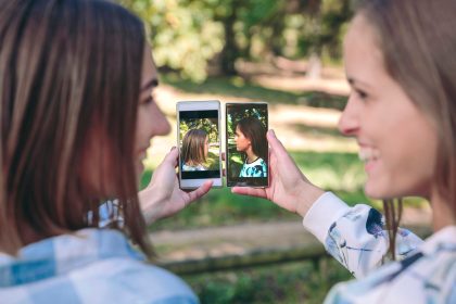 Szczęśliwe kobiety pokazujące smartfony z widokiem z boku na zdjęcia portretowe zrobione nad lasem