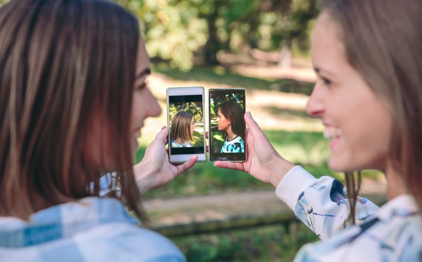 Szczęśliwe kobiety pokazujące smartfony z widokiem z boku na zdjęcia portretowe zrobione nad lasem