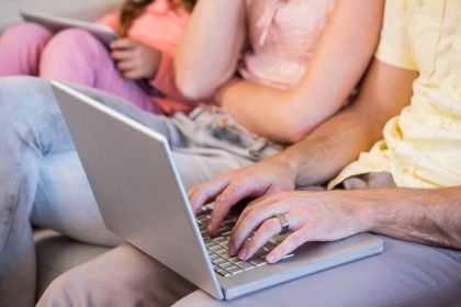Rodzina na kanapie przy użyciu komputera typu tablet i laptopa