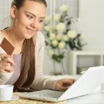 Młoda piękna kobieta z wizytówką za pomocą laptopa, w pomieszczeniu