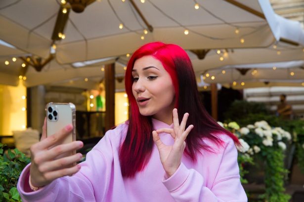 Piękna rudowłosa influencerka blogger dziewczyna w kawiarni rozmawia rozmowy wideo za pomocą smartfona z subskrybentami w sieciach społecznościowych.