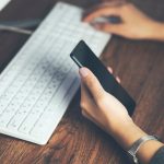 Kobieta ręka telefon z działającą klawiaturą na stole