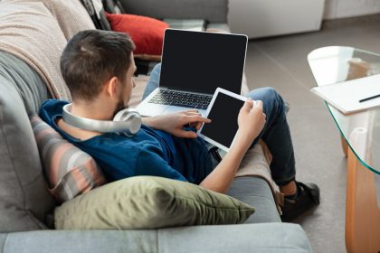 Młody skupiony mężczyzna uczący się samodzielnie w domu podczas kursów online lub bezpłatnych informacji. Zostaje twórcą oprogramowania, menedżerem IT, gdy jest odizolowany, poddany kwarantannie. Korzystanie z laptopa, smartfona, słuchawek.