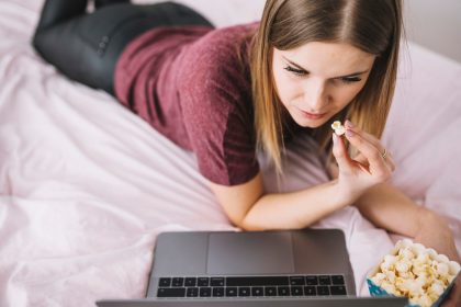 Kobieta z popcornem ogląda film na laptopie