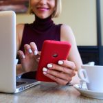 Zbliżone zdjęcie białej kobiety używającej smartfonu do pracy na odległość w kawiarni